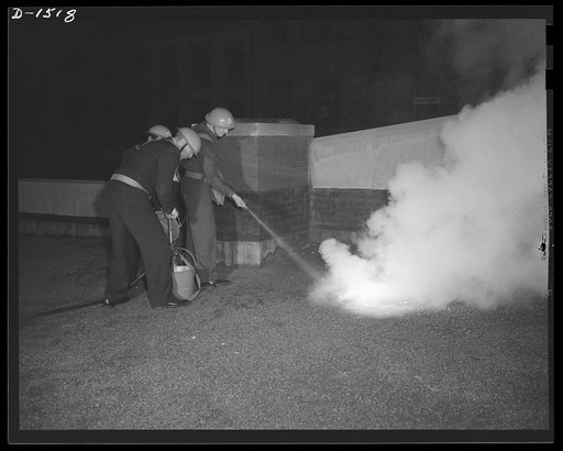 Civilian defense. Extremely valuable in battling incendiary bombs is the stirrup pump operated by three, or in cases of emergency, two men. The volunteer worker closest to the camera is pumping water from the bucket on the reef, while the man barely visible in the center replenishes the water supply