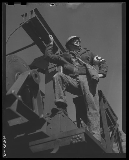 Civilian protection. Member of a demolition and clearance Squad takes his place on the winch-equipped truck used in his squad's operations