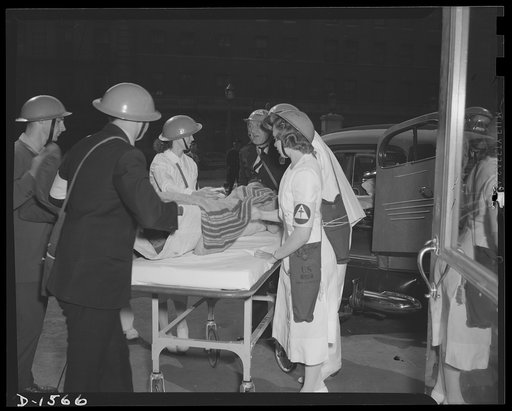 Civilian protection. A seriously injured victim of a bomb raid is removed from a casualty clearing station to hospital via ambulance