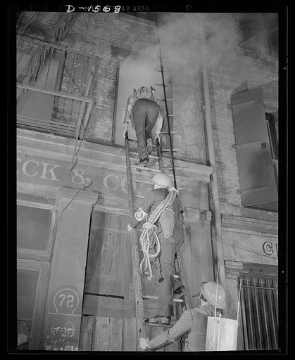 Civilian protection. Fully equipped to cope with any situation they may encounter these New York City volunteer auxiliary firemen put on a demonstration of the matter in which they would handle the damage caused by an incendiary bombing attack. An incendiary bomb has fallen through the roof of this 
