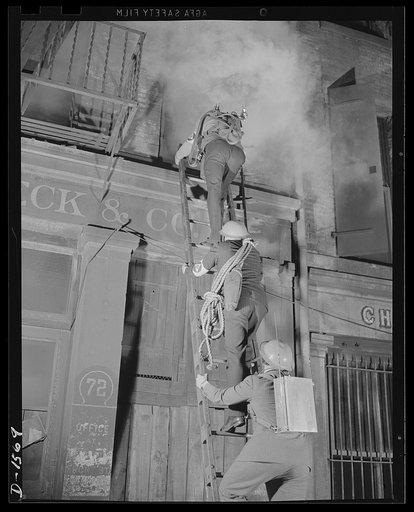 Civilian protection. Fully equipped to cope with any situation they may encounter these New York City volunteer auxiliary firemen put on a demonstration of the matter in which they would handle the damage caused by an incendiary bombing attack. An incendiary bomb has fallen through the roof of this 