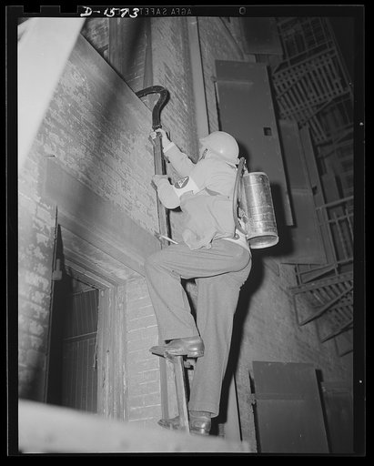 Civilian protection. A New York City volunteer auxiliary firemen illustrates in a demonstration in New York his efficiency in the event of an incendiary bombing attack. This worker, equipped with an "Indian" fire pump, is mounting a scaling ladder to the roof of a building on which several incendiar
