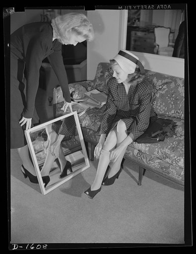 Cotton stockings. Cotton is coming to have universal appeal. Shopping for cotton hose in a Hollywood store, Rita Hayworth finds that the shop girl, too, is wearing hose much the same type she plans to buy. Miss Hayworth is inspecting a diamond pattern lisle stocking personally selected for her by Ho