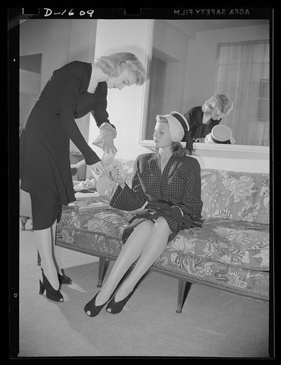 Cotton stockings. Cotton is coming to have universal appeal. Shopping for cotton hose in a Hollywood store, Rita Hayworth finds that the shop girl, too, is wearing hose much the same type she plans to buy. Miss Hayworth is inspecting a diamond pattern lisle stocking personally selected for her by Ho