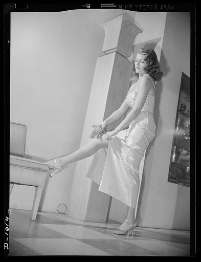 Cotton stockings. Rita Hayworth in a pink and silver lame evening dress, designed by the famed Hollywood designer, Howard Greer. Her evening hose are of fine crepe lisle of the same spun sugar sheen as the dress