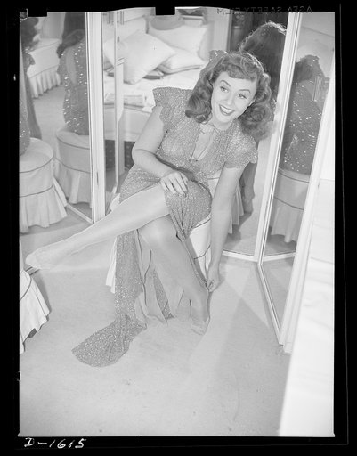 Cotton stockings. Paulette Goddard illustrates the new fashion trend of having her hose blend in color with her evening dress. The dress she wears is of gold bugle beads, designed by the famous Hollywood designer, Edith Head. Her stockings are gold-colored sheer crepe lisle