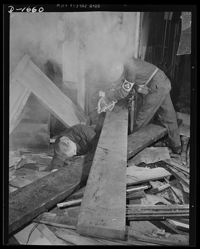 Civilian protection. This portable electric saw is one the useful tools carred by and powered from the emergency service truck. Here a member of a rescue squad (note the armband) is sawing through a timber to enable him to extricate a bombing victim beneath it