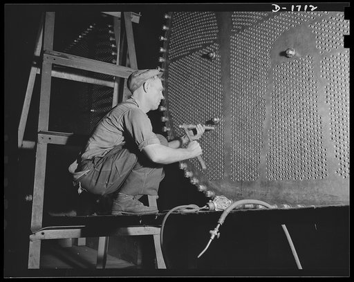 Shipbuilding (Newport News). This worker is touching up one of the huge condensers for a U.S. Navy destroyer under construction
