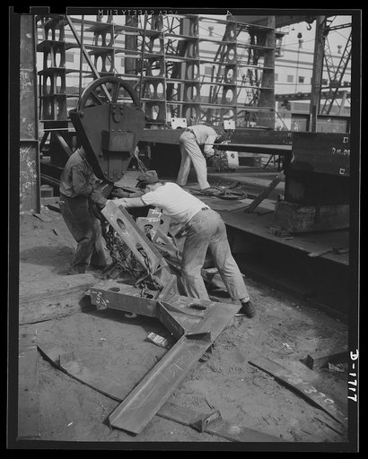 Shipbuilding (Newport News). These workers are attaching parts for a new cruiser under construction to the overhead crane which will deliver the metal to the building ways