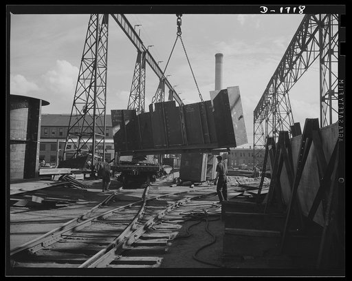 Shipbuilding (Newport News). A section for a new U.S. Navy cruiser is being delivered by overhead crane to the building ways. Four cruisers and a battleship are under construction here