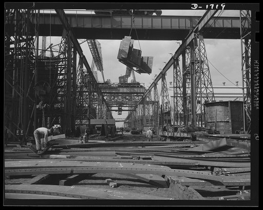 Shipbuilding (Newport News). A section for a new U.S. Navy cruiser is being delivered by overhead crane to the building ways. Four cruisers and a battleship are under construction here