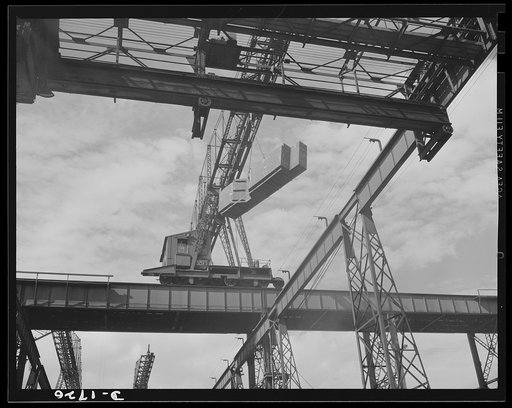 Shipbuilding (Newport News). A section for a new U.S. Navy cruiser is being delivered by overhead crane to the building ways. Four cruisers and a battleship are under construction here