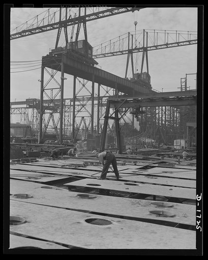 Shipbuilding (Newport News). In the shadow of the huge building ways. where four cruisers and a battleship for Uncle Sam's growing navy are under construction, lies the ship's plate section. The plates are carried from here to the ways by large overhead cranes