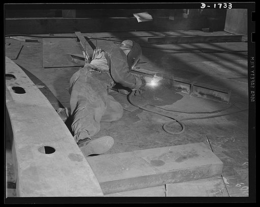 Shipbuilding (Norfolk Navy Yard). This welder is torch flaming a part for a new destroyer on the ways at the Norfolk Navy Yard. Riveted joints have been cut down by as much as two-thirds in the last few years, as welding has been developed to a point where it provides equal strength. Welding means l