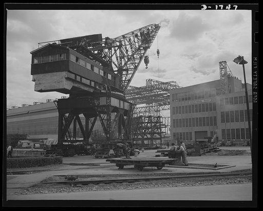 Shipbuilding (Norfolk Navy Yard). This is one of the huge cranes used to transport heavy parts and sections from one part of the yard to another. Cranes such as these take sections from the various structural shops to the buildings ways