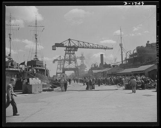 Shipbuilding (Norfolk Navy Yard). It's lunch time, and thousands of workers are taking their thirty minutes of recreation. To the left are two ships in for minor repairs, while in the background are a pair of huge overhead cranes used to swing heavy parts into position for the various shipbuilding o