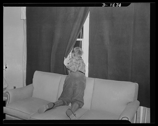 Air raid protection--what NOT to do when alarm sounds. DON'T look out the windows. Johnnie doesn't mean to be a fifth columnist, but in looking out and attempting to see the planes he's flashing a swell signal just the same; in addition this is a dangerous place for him to be because of flying glass