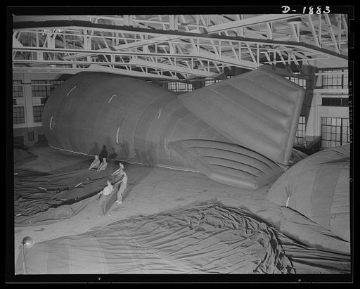Barrage balloon manufacture. Tugging a finished half of a barrage balloon into position for joining with the other half. These workers have come to the final assembly step in producing barrage balloons for American air defense. Four steps in final production are shown in this photo: the half-balloon