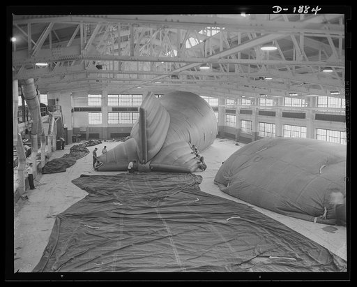 Barrage balloon manufacture. Birthplace for air-whales--gigantic barrage balloons which look like monster whales-of-the-air, made in this huge room. Four are seen here: left rear is a balloon being folded into the shipping container at the extreme rear; next to it is an inflated balloon on which fin