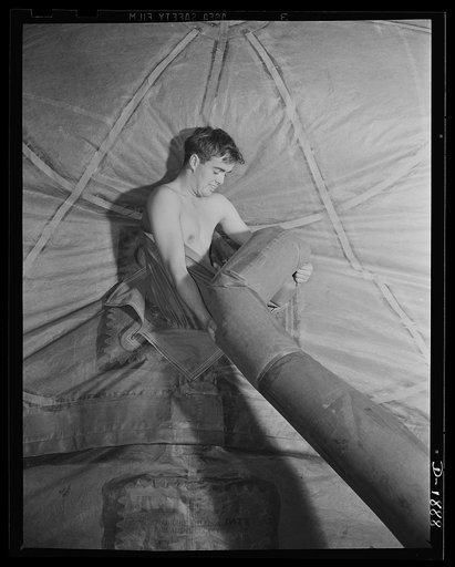 Fill 'er up! Tugging at the large hose, known as the "inflation sleeve", this worker stands inside the "manhole" of a new barrage balloon to guide the sleeve into the opening through which it will pump air to test the giant rubber balloon for leaks. General Tire and Rubber Company, Akron, Ohio