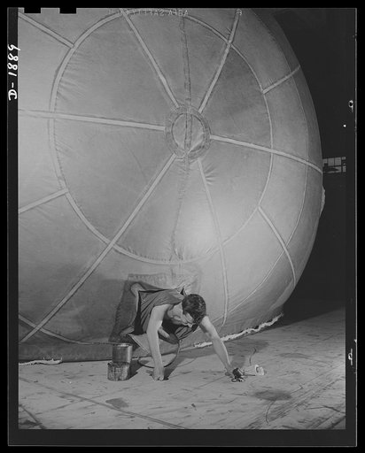 Barrage balloon manufacture. All out for defense! Scrambling out of the zipper-covered "manhole" in the nose of a gigantic barrage balloon, this worker has finished patching, touching up and checking the great bag, and is ready to give the signal to deflate the balloon, pack it and ship it to Uncle 