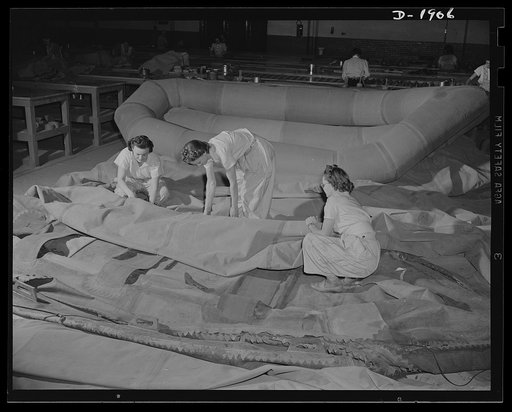 Assault boat Production. Building assault boats for U.S. Marine Corps. Woman workers lay out partially-assembled boat preparatory to inflating so that fixtures and other finishing touches may be applied. Goodyear, Akron, Ohio