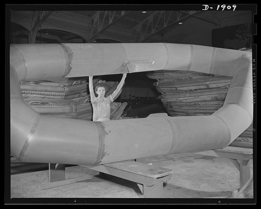 Assault boat Production. Building assault boats for U.S. Marine Corps. These inflatable boats are so light that during the process of their construction they may be readily turned over by a single employee as shown in this picture. When work is completed on one side, the boats are turned to permit w