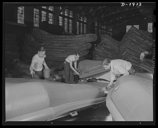 Assault boat Production. Building assault boats for U.S. Marine Corps. Workmen apply final coating of rubber paint preparatory to deflating boats and packing for shipment. Goodyear, Akron, Ohio