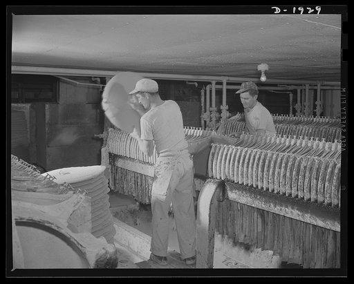 Removing cakes of clay from one of a battery of filter presses. This operation precedes the pug mill. Shenango Pottery Works, Newcastle, Pennsylvania
