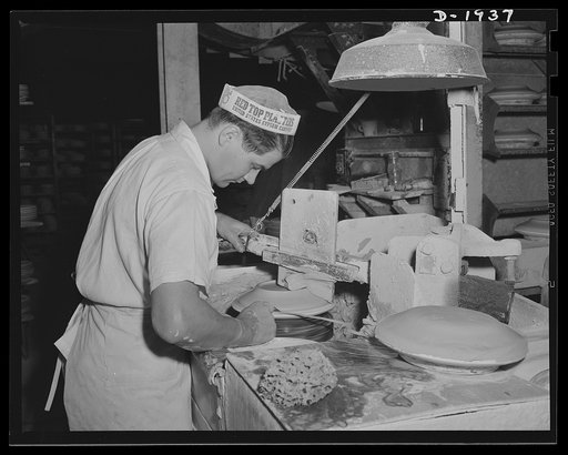 Forming the back of a plate. This process is known as jiggering. A plaster of Paris mould forms the shape of the face of the plate. Shenango Pottery Works, Newcastle, Pennsylvania