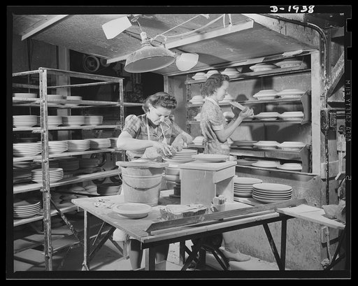 The girl on the right is removing dried plates from the plaster of Paris moulds after the surveyor has carried them into the drying chamber for several hours. The girl on the left is sponging small imperfections from the surface and trimming the edges. Shenango Pottery Works, Newcastle, Pennsylvania