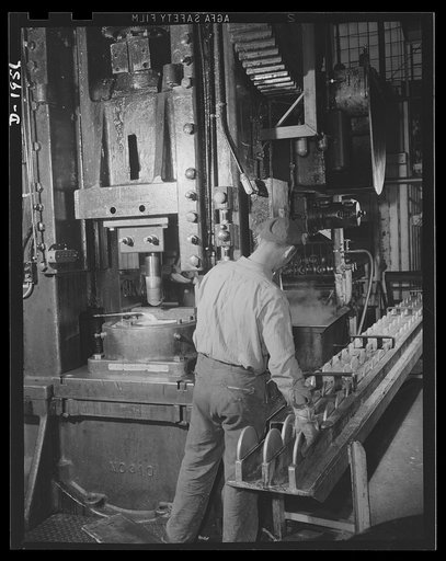 Three-inch A.A. cartridge cases. The art of metal drawing is employed to turn brass discs punched from rolled sheets into long tubular cartridge case to carry the powder charges that send explosive shells up to meet enemy aircraft. The first operation is performed by a press which forms the flat dis