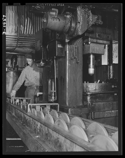 Three-inch A.A. cartridge cases. Brass discs are conveyed to a cupping press that forms them into the brass cups from which cartridge cases for three-inch antiaircraft shells are drawn. They look harmless enough but each one will be a potential headache for Axis fliers by the time it comes off the p