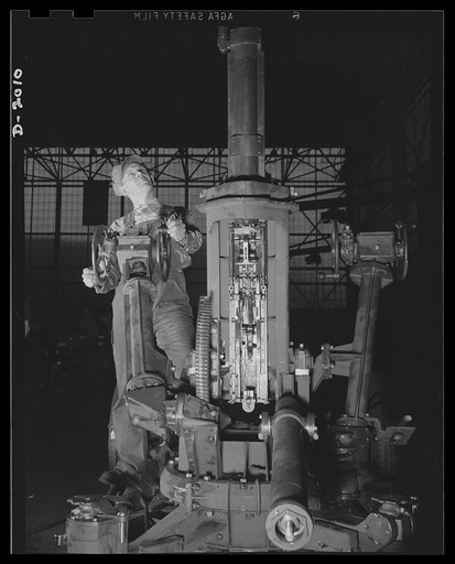 Antiaircraft gun carriage. A worker tests the smooth working precision of the elevating mechanism assembly of a thirty-seven-millimeter anti-aircraft gun carriage. Planes of 300 miles an hour and better present a fast-moving target which requires precision operation in the anti-aircraft gun that mus
