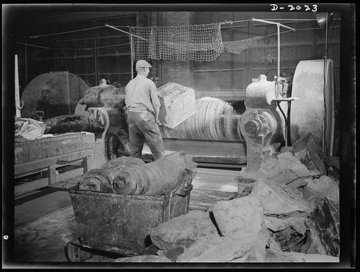 Last grain of powder is dumped into the mill hopper as another hatch is completely filled. Next batch is in the foreground but will not be started until the present one is completely mixed. Mixing time varies with the characteristic of the batch, both as to the number of ingredients and the speed wi