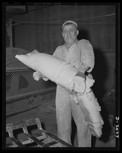 Off to the calendaring machine. The finished batch is taken by other tire workers to the next step in the milling process. In this instance, the batch goes from the mill room to the calendaring machine, where it will become a part of the cord fabric. Firestone (General Tires), Akron, Ohio