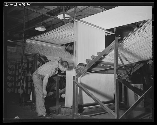 Feeding cord to the fabric machine. Cords feed down through the floor to the calendaring machine two stories below. As may be seen from this picture, the cords are gathered in four banks at this point, but join together in a solid mass by the time they reach the rubber-impregnating calendaring machi