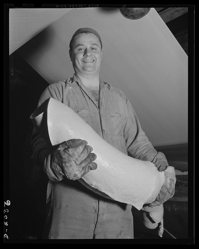Replenishing gum rubber for tire cords. A new supply of gum for the fabric is being carried to the calendaring machine by this worker. After having been milled originally by processes previously described, the moment of impregnation by auxiliary mills alongside the calendaring machine. Firestone (Ge