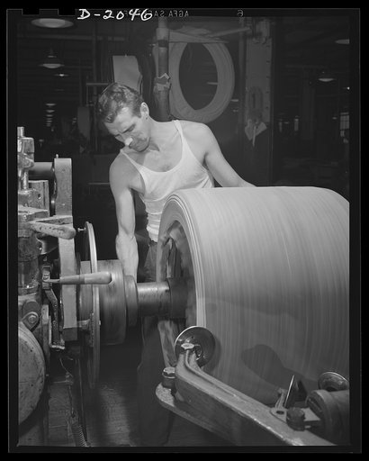 Shaping the tire with "saucers." Spinning discs which are delicately controlled by movable arms smooth out each layer of fabric as it is added to the growing carcass, and curves around the sidewall and bead with considerable pressure. In the center foreground, one of these saucers may be seen as thi
