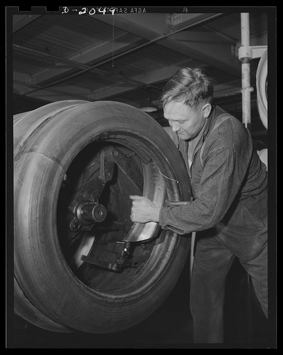 Removing the finished tire from the tire drum. The inner drum shoes are unlocked after the tire is loosened; They are removed, leaving the tire free to slide right off. Then they are replaced and the next tire is started. Firestone (General Tires), Akron, Ohio