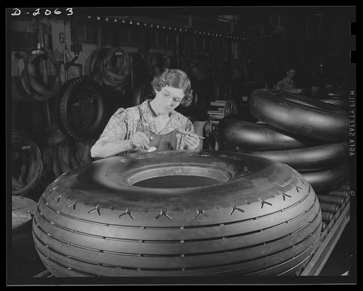 Marking point for the valve stem. These tires are so perfectly balanced that the weight of the valve stem is allowed and provided for. This woman attaches a label to the tire at the point where the valve stem should be placed. Balancing a tire was once considered unneccessary, until it was demonstra
