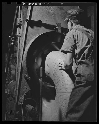 Wrapping the finished tire. Seeing is not necessarily believing. Even when you see the tire-wrapping machine in operation, it is difficult to understand how it works....spinning a strand of paper around a tire as fast as the operator can feed them in. All the operator need do is place the tire in po