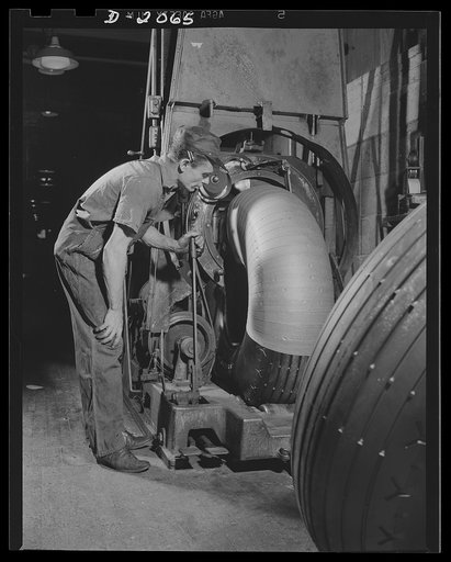 Wrapping truck tires. All sizes of tires can be wrapped by this machinery, which has an opening just large enough for the tire to pass through. It throws a semi-circular catapult through the middle of the tire; the catapult carries the roll of paper with it, unwinding as it goes. Firestone (General)