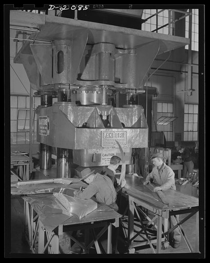 Subcontracting aircraft parts. These workers at the huge airship dock, now converted to war production, are preparing dies for insertion in a powerful hydraulic press. Many parts of the aircraft for democracy are stamped out in presses such as these. Goodyear, Akron, Ohio