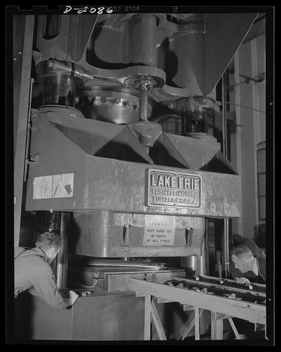 Subcontracting aircraft parts. This giant hydraulic press with rubber insert is used to stamp out numerous sub-assembly parts for planes at this huge converted airship dock. These "sub-assembly" parts are put together at the different plants and then sent to the plane plants for inclusion in the fin