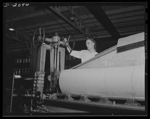 Subcontracting aircraft parts. This worker at a large Ohio plant, is shaping a large piece of aluminum into the desired conture for fitting leading edges of the various control surfaces and outer wings. Goodyear, Akron, Ohio