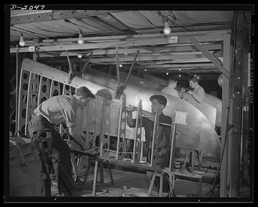 Subcontracting aircraft parts. Here is one of the airplane sub-assembly production lines at an Ohio plant, which was a former airship dock. These are control surfaces for military aircraft, being assembled here for shipment to plane plants. Goodyear, Akron, Ohio