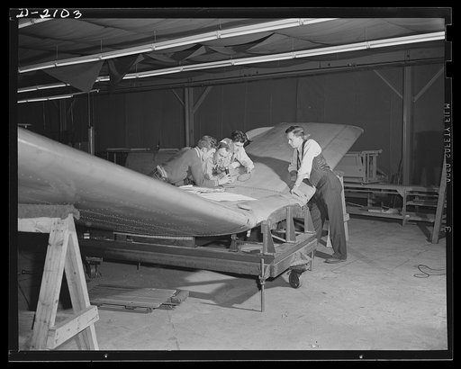 Subcontracting aircraft parts. A flashlight is called into play as these U.S. Navy (USN) inspectors go over every portion of the huge stabilizer just assembled at an Ohio plant. Goodyear, Akron, Ohio