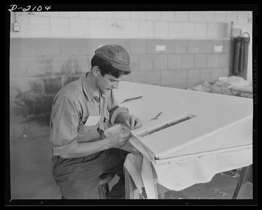 Subcontracting aircraft parts. This young worker is an expert at sewing fabric onto movable control surfaces. The section on which he is now working, at this huge Ohio plant, will eventually be part of a U.S. bombing plane. Goodyear, Akron, Ohio