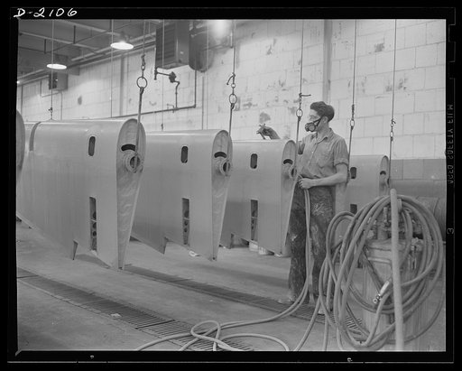 Subcontracting aircraft parts. Here is the "dope room" at a huge Ohio plant. The fabric covering control surfaces for military aircraft is here doped, or covered with protective paints. This worker is spraying  surfaces with a special lacquer to make them glossy and weather-proof. Goodyear, Akron, O